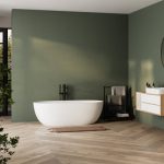 Modern minimalist bathroom interior, bathtub and bathroom cabinet, white sink, interior plants, bathroom accessories, parquet floor, green wall.